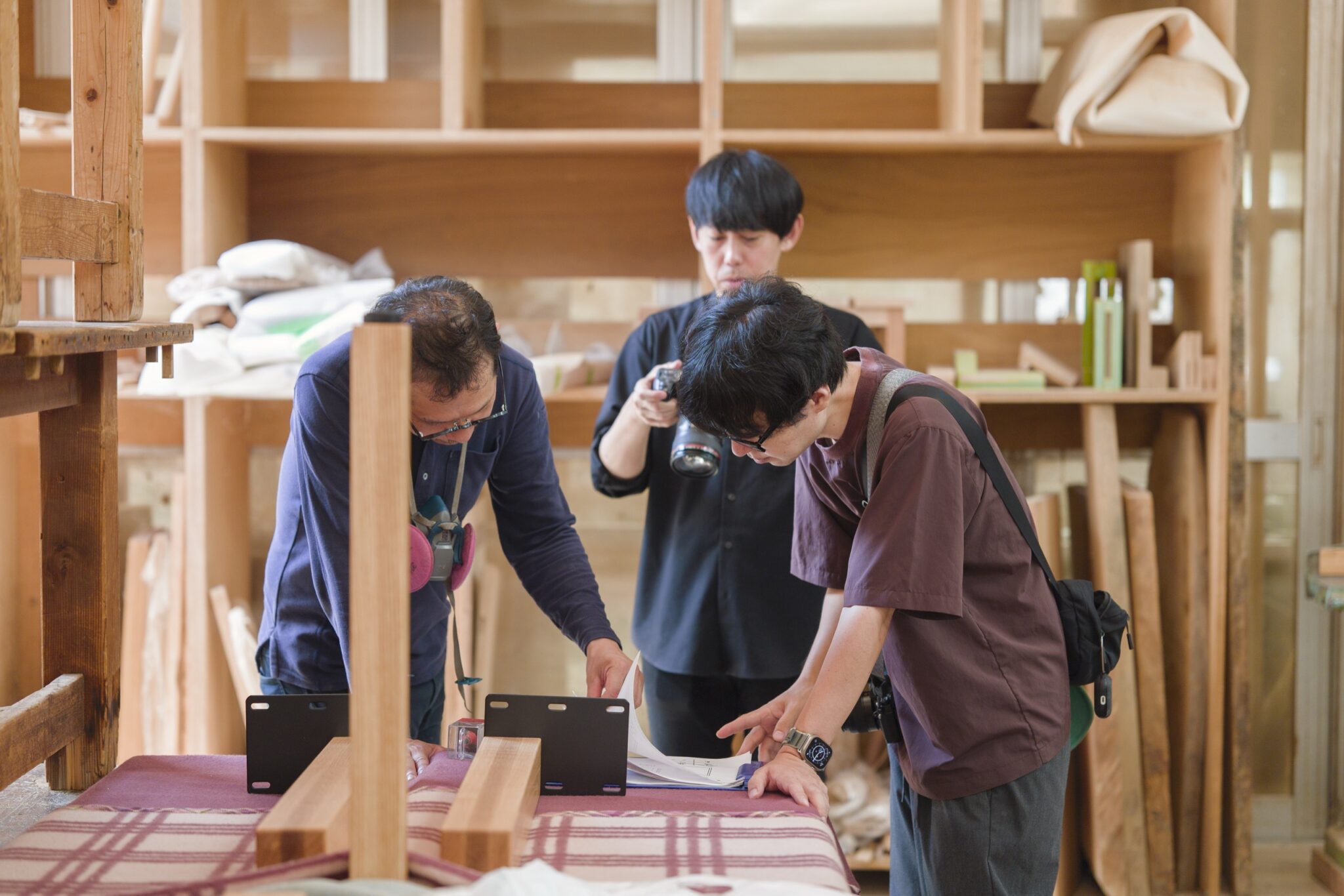 工房で額縁の寸法を検討しているところ　作業台に材を置いて確かめている
